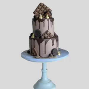 Chocolate cake topped with Cadbury chocolate bars and cookies, with melted chocolate dripping around the top tier and flowing to the first layer.